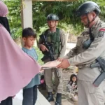 Personel Satagas Madago Raya menyerahkan seragam Merah Putih kepada seorag anak di wilayah Operasi, Poso, Minggu (9/2/2025). (Foto: HUmas Ops Madago Raya)