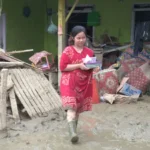 Warga membawa barangnya melintasi lumpur yang menggenangi rumahnya pascabanjir bandang di Desa Wombo, Kecamatan Tanantovea, Kabupaten Donggala, Sulawesi Tengah, Sabtu (31/5/2025). (bmzIMAGES/Basri Marzuki)